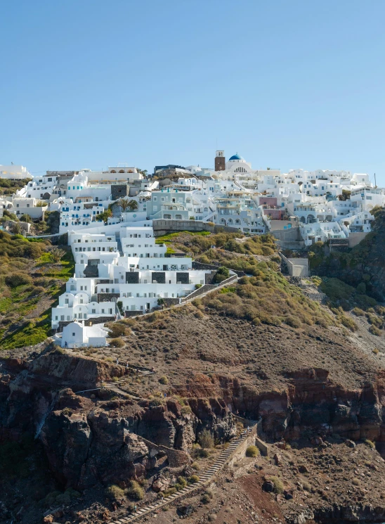 a hill covered in white buildings sitting on top of a green hillside