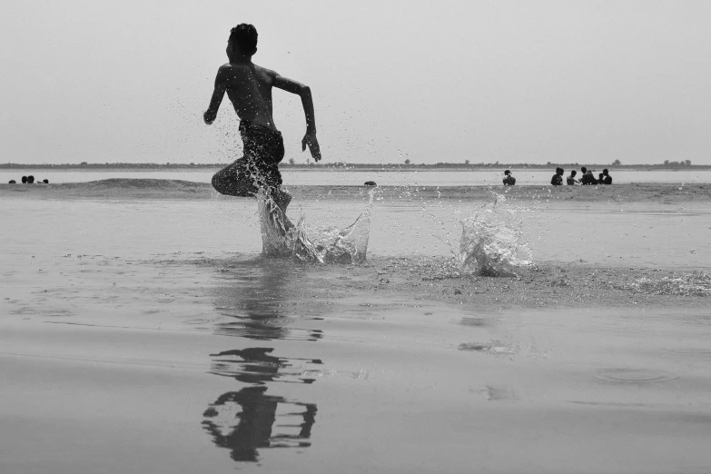 a man kicking up some water near the beach