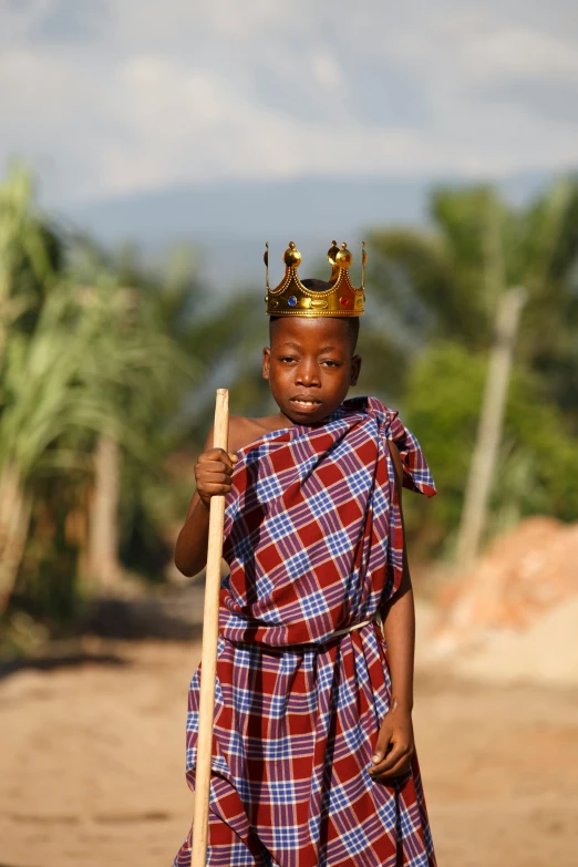 a little girl in plaid dress holding a stick