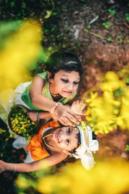 two little girls wearing yellow and white dresses playing around