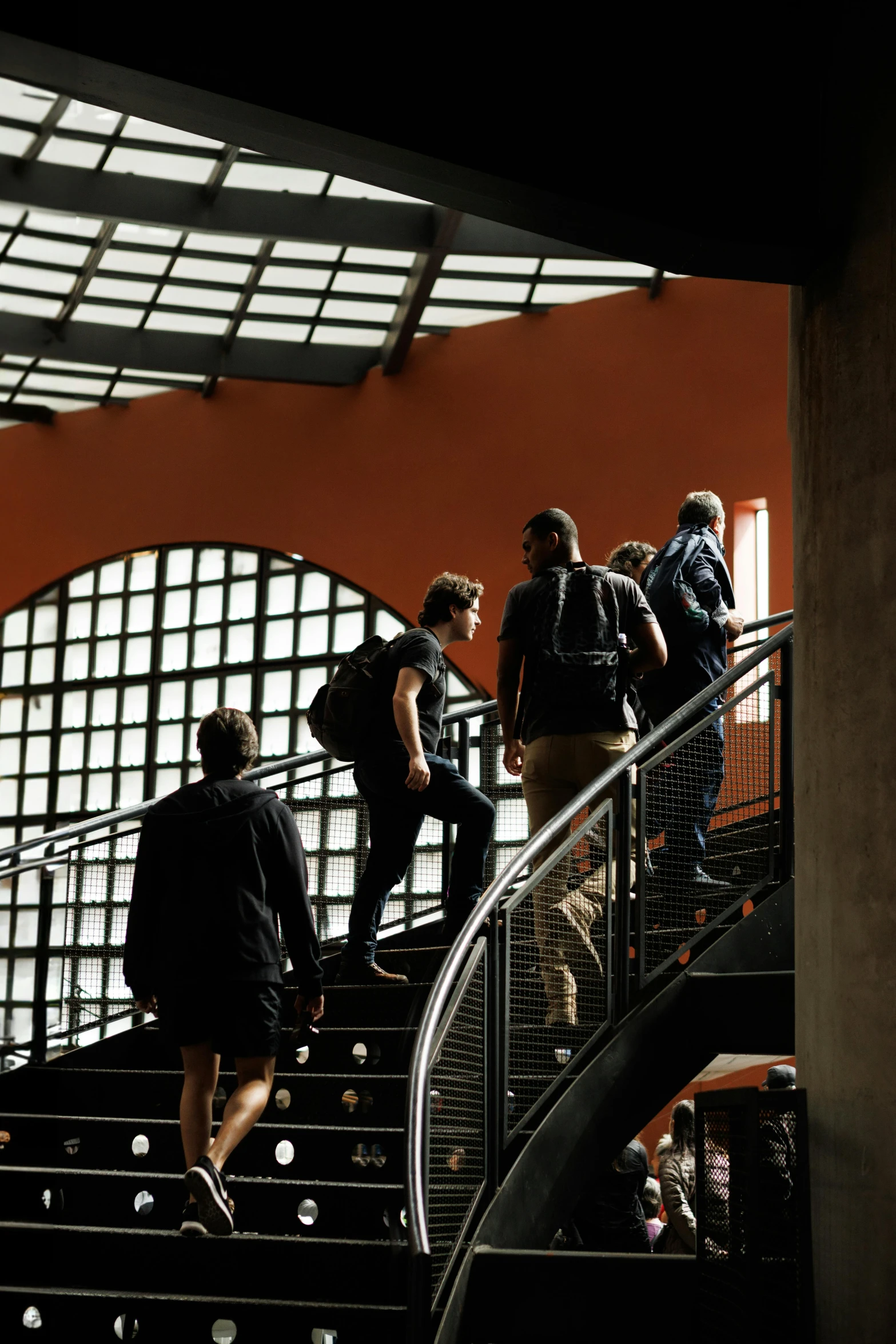 people walking down a flight of stairs in front of a sunlit window