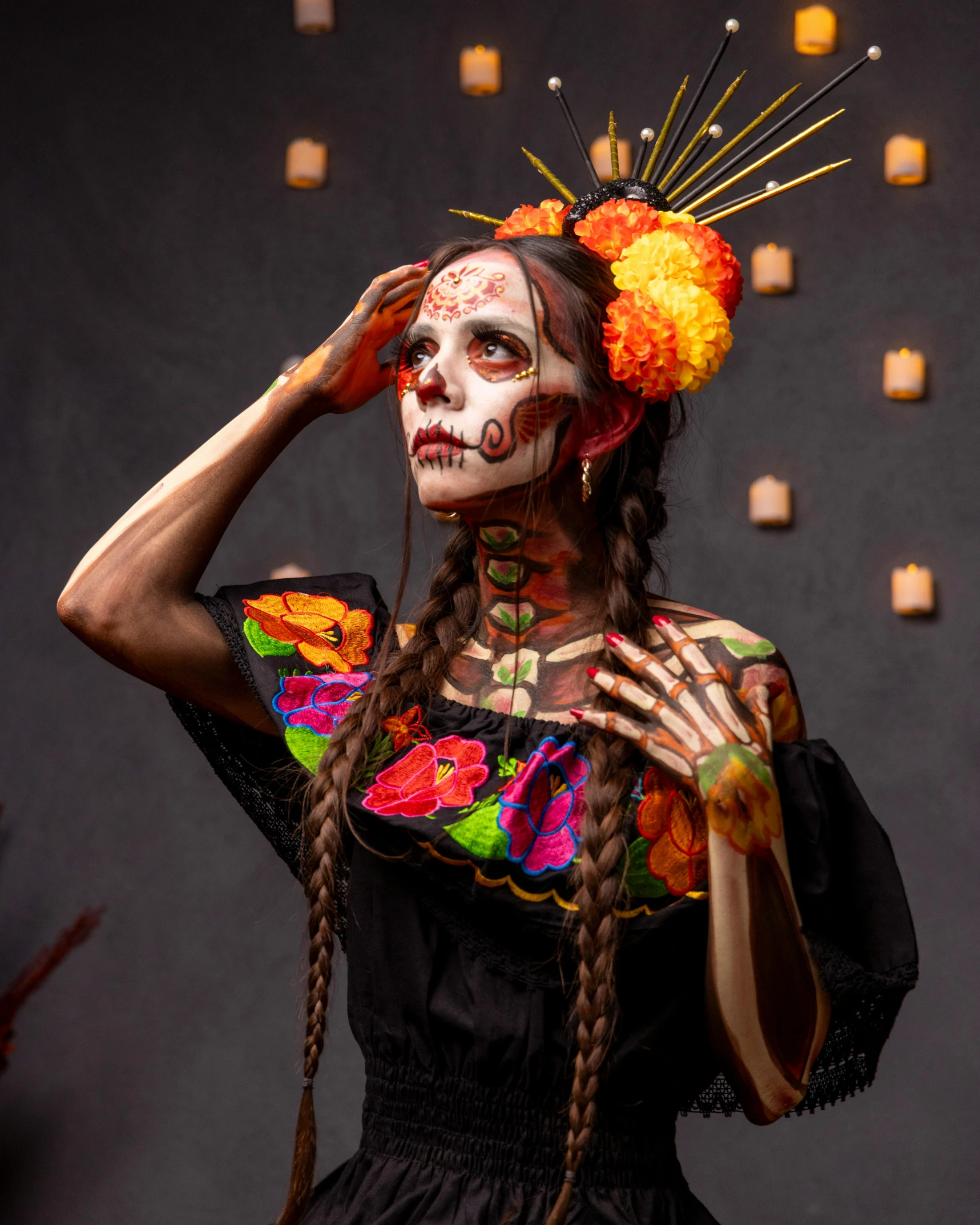 a woman with facial paint and ids holds her head to one side, wearing an elaborate skull make up and wreath around her face