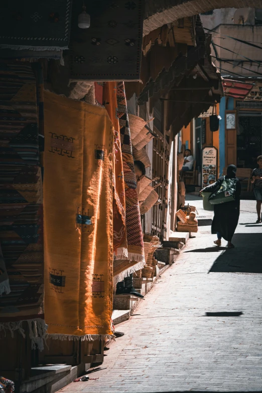 the person is walking down the narrow sidewalk in the village