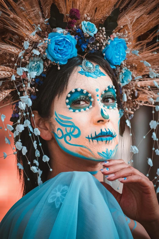 a woman wearing blue makeup and feathers