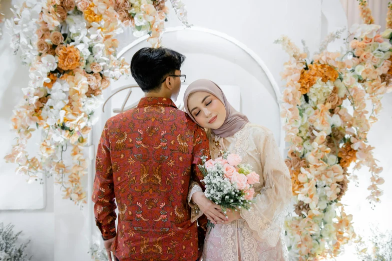 a couple dressed in traditional indian dress standing under an archway with floral decorations