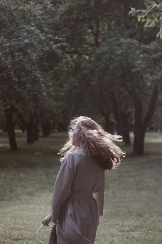 a young woman standing in the grass holding an umbrella