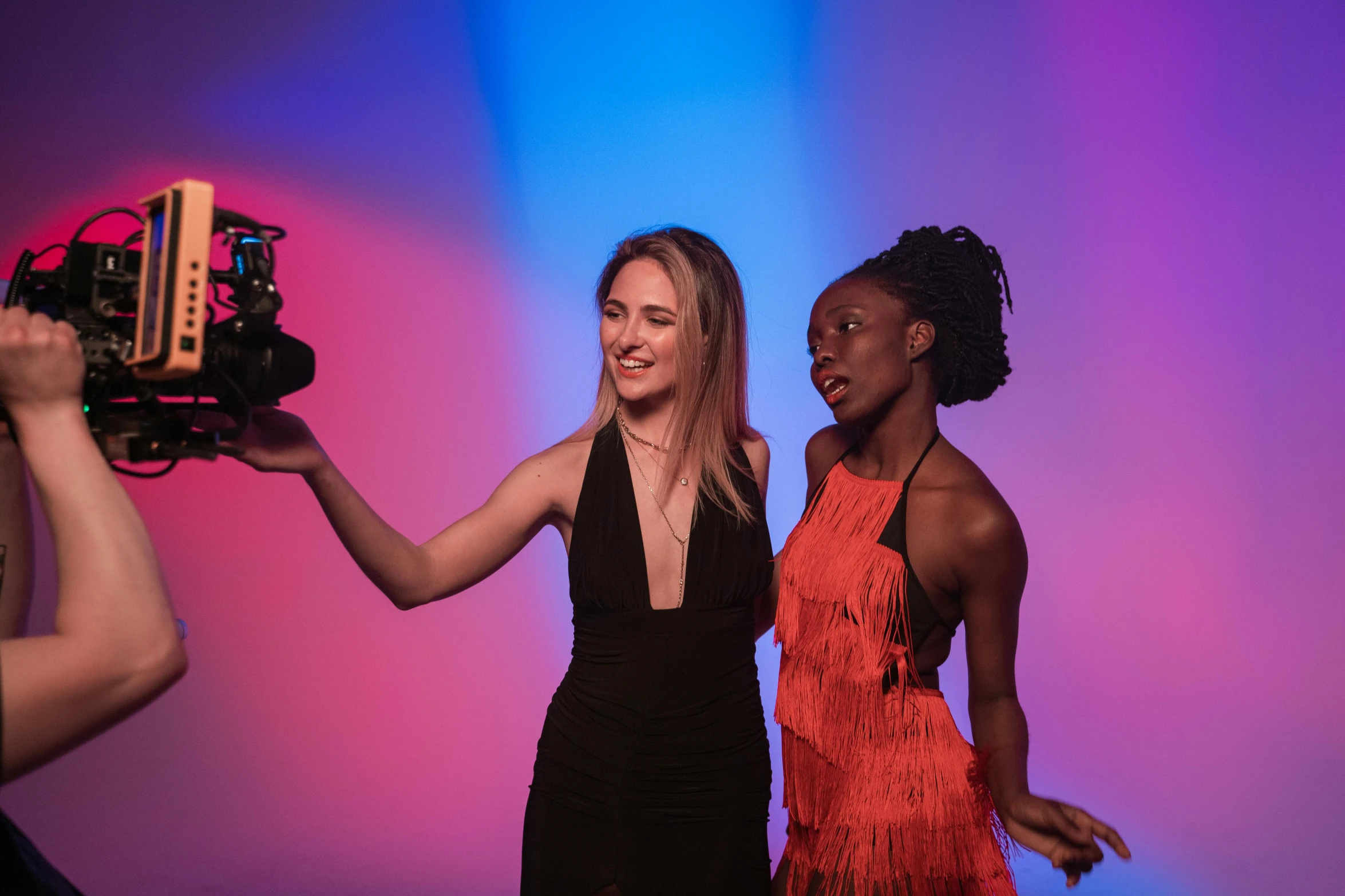 two women standing in front of a video camera