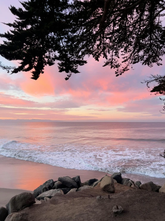 a scenic view of the ocean with pink and blue clouds