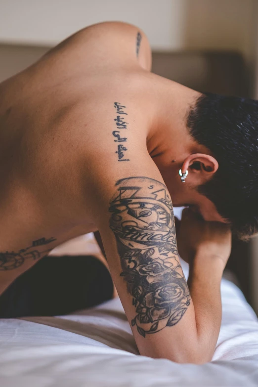 a man is on his bed with tattoos on his body