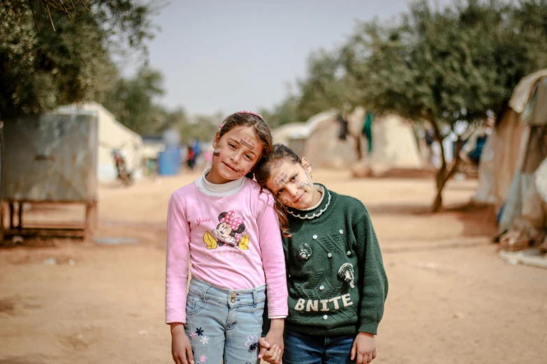 two children in dirty clothes stand next to each other