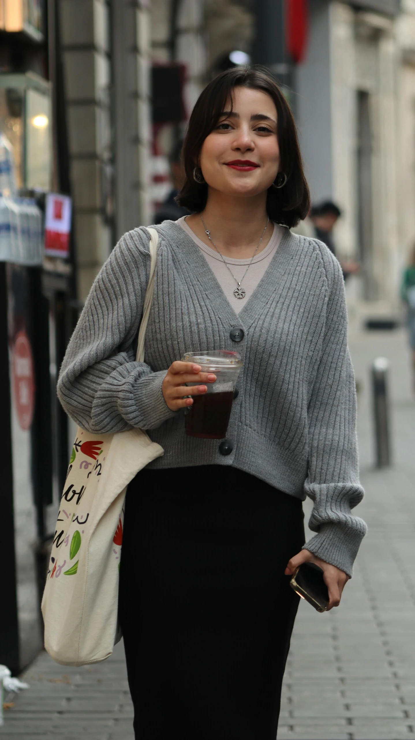 an attractive woman with a large cup and a purse on the street