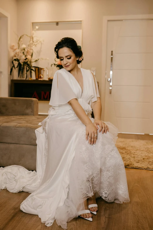 a woman in a white wedding dress sitting on a wood floor