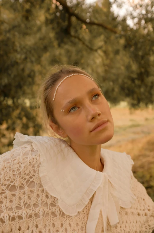 a woman wearing white stands near trees