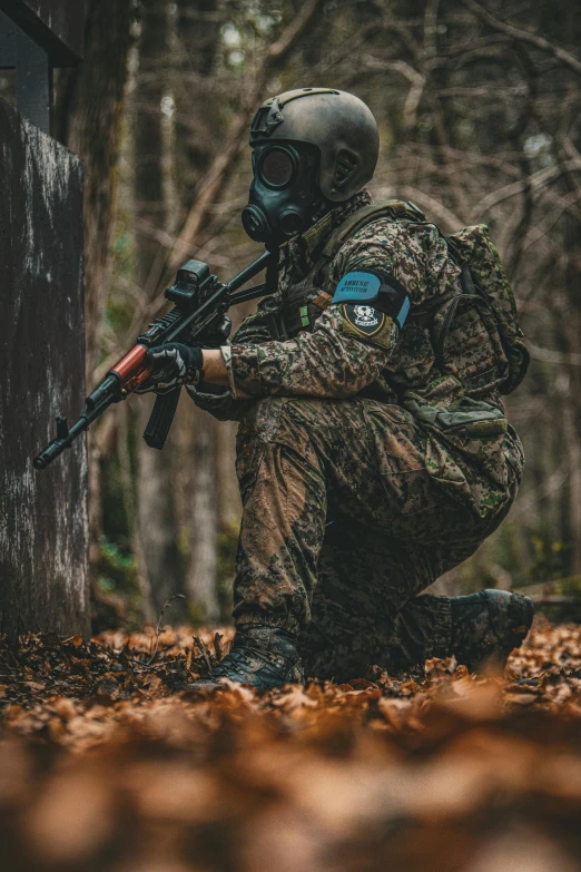 an armed soldier crouching and holding his rifle