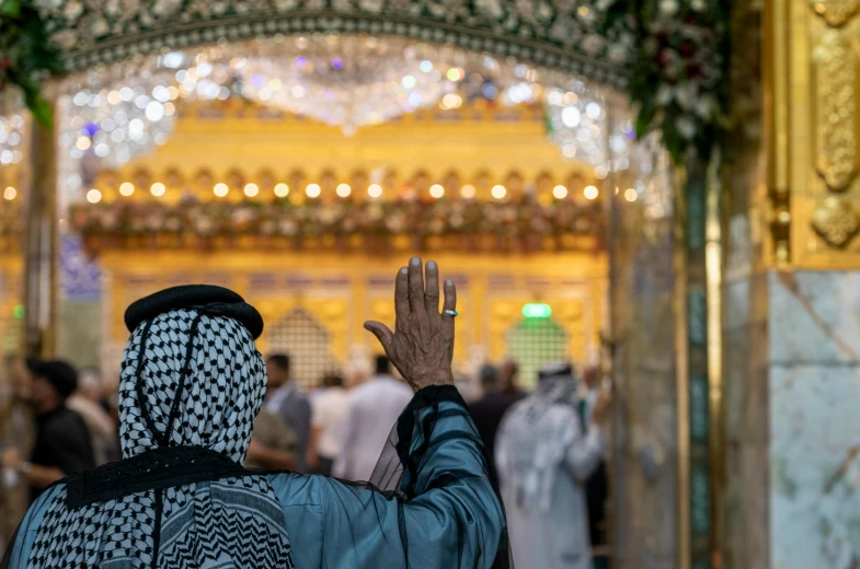 a man in a patterned robe praying inside an ornate structure