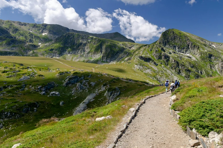 people with backpacks walking up a rocky path