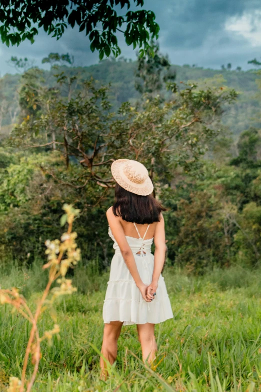 woman standing on grassy area with trees in background