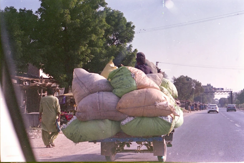 bags on a car's flatbed with workers hing them