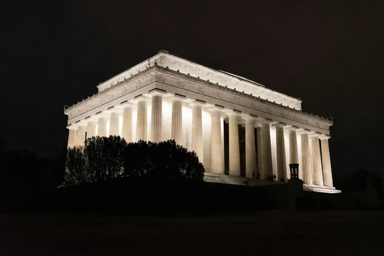 lincoln memorial lit up at night with trees and bushes around it