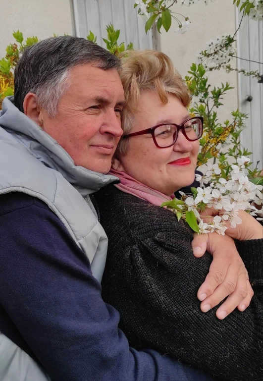 a man is hugging the shoulders of a woman in front of flowers