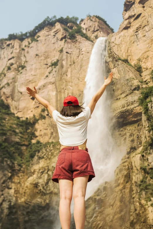 woman reaching up for a waterfall above her head