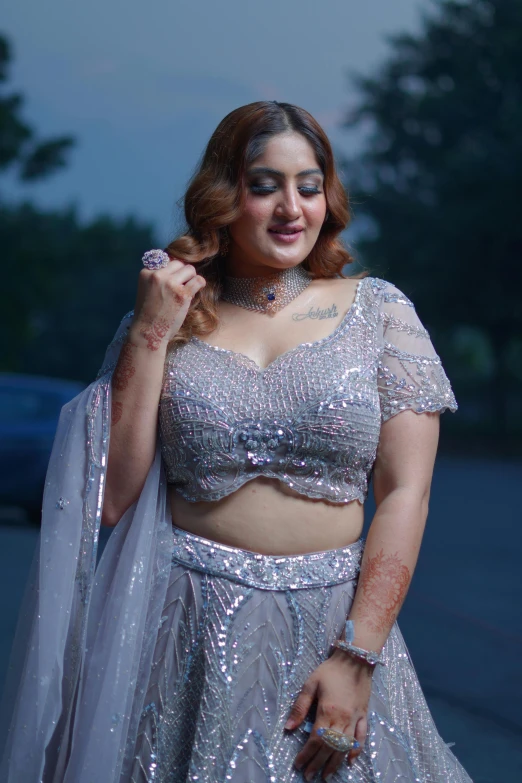 woman dressed up and standing on the side of road in silver sari