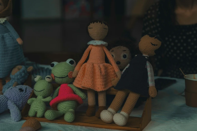 several stuffed animals sit on a table while one stands with her hand on the back of her head