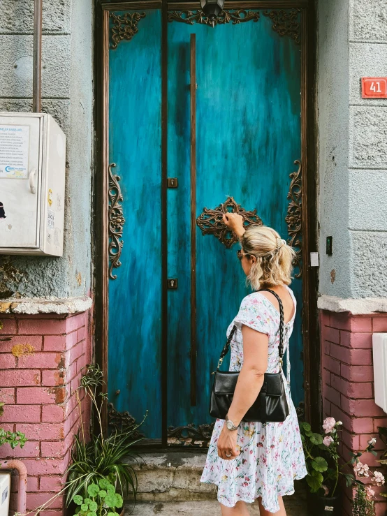 woman taking selfie in front of blue door on pink building