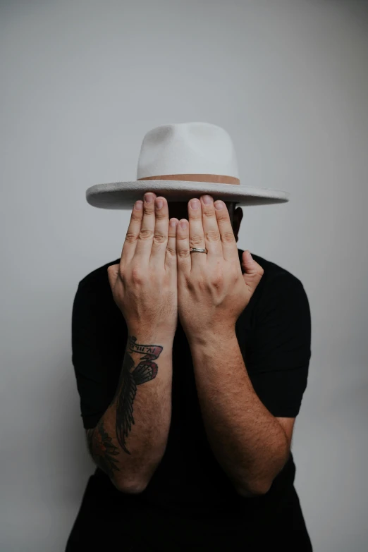 a man covering his eyes in a hat