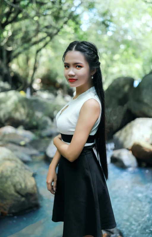 a beautiful woman standing by a creek in a dress