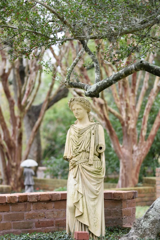 a statue standing on a wall near some trees