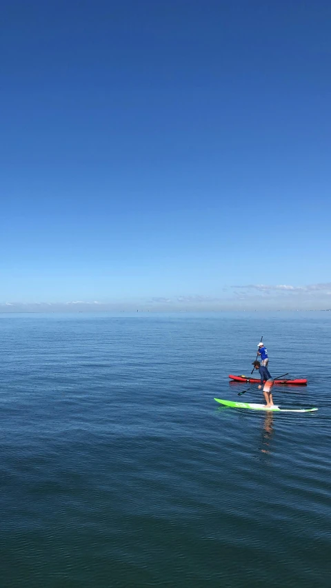 two people riding surf boards on top of water