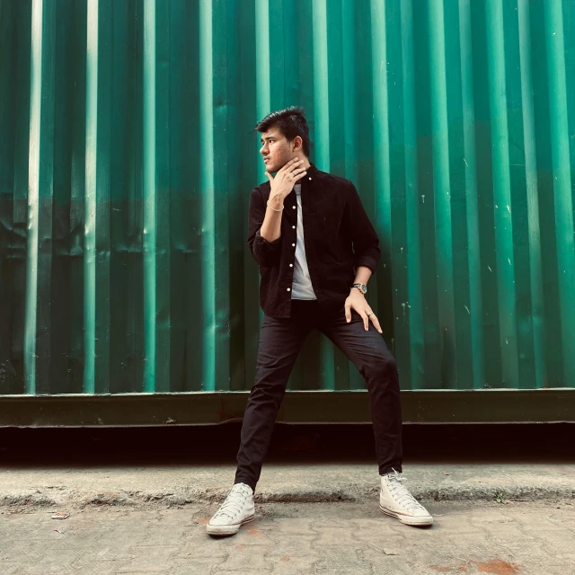 a man leaning on a metal green wall