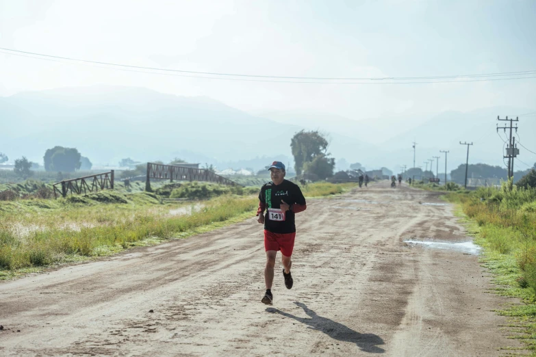 there is a male athlete running on a dirt road