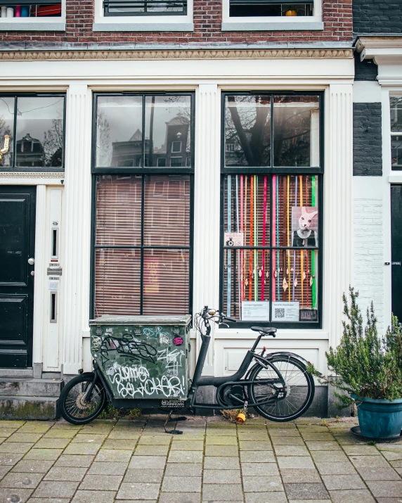 a black bicycle is parked next to a brick building with window