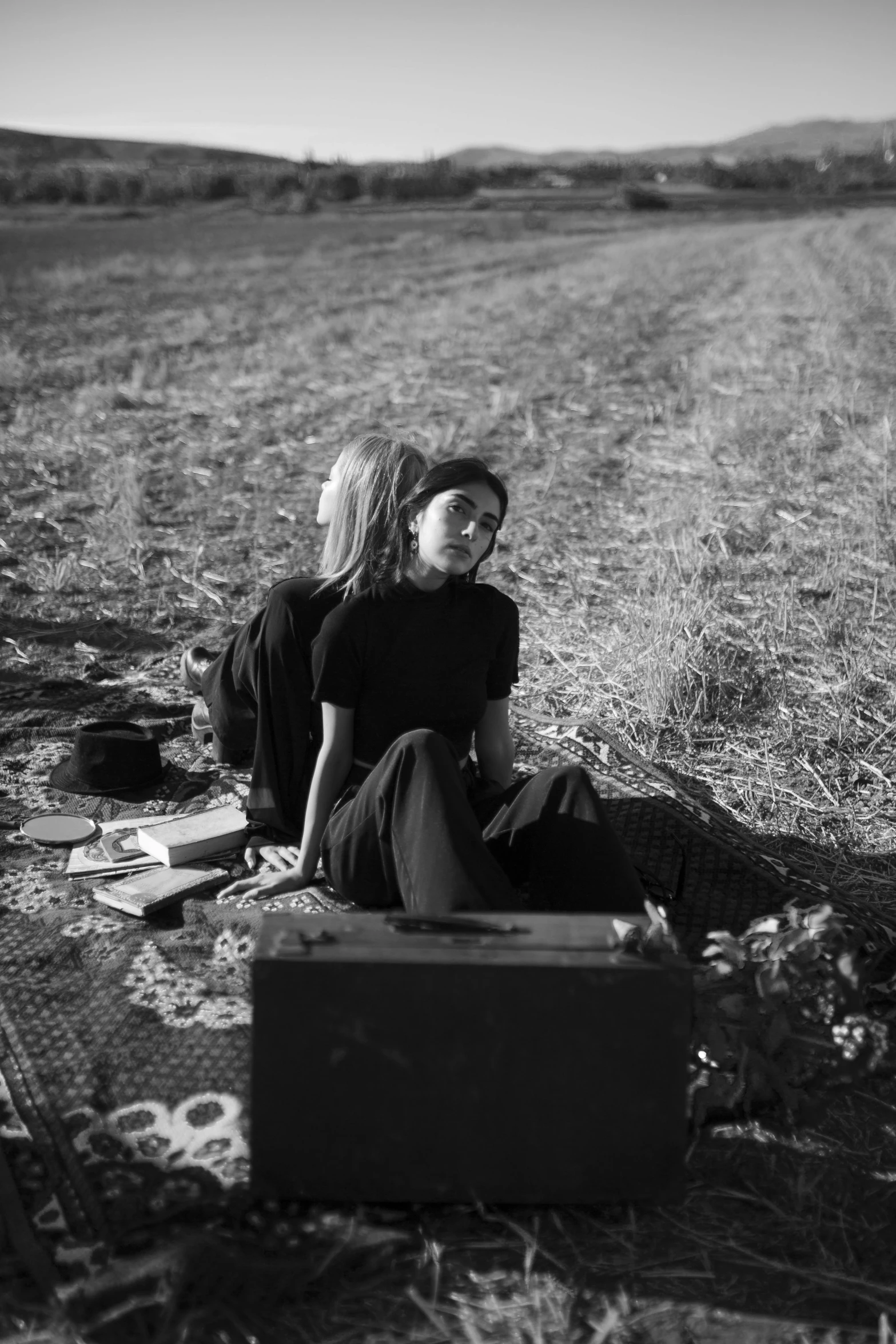 two girls sitting on the ground looking at an open suitcase