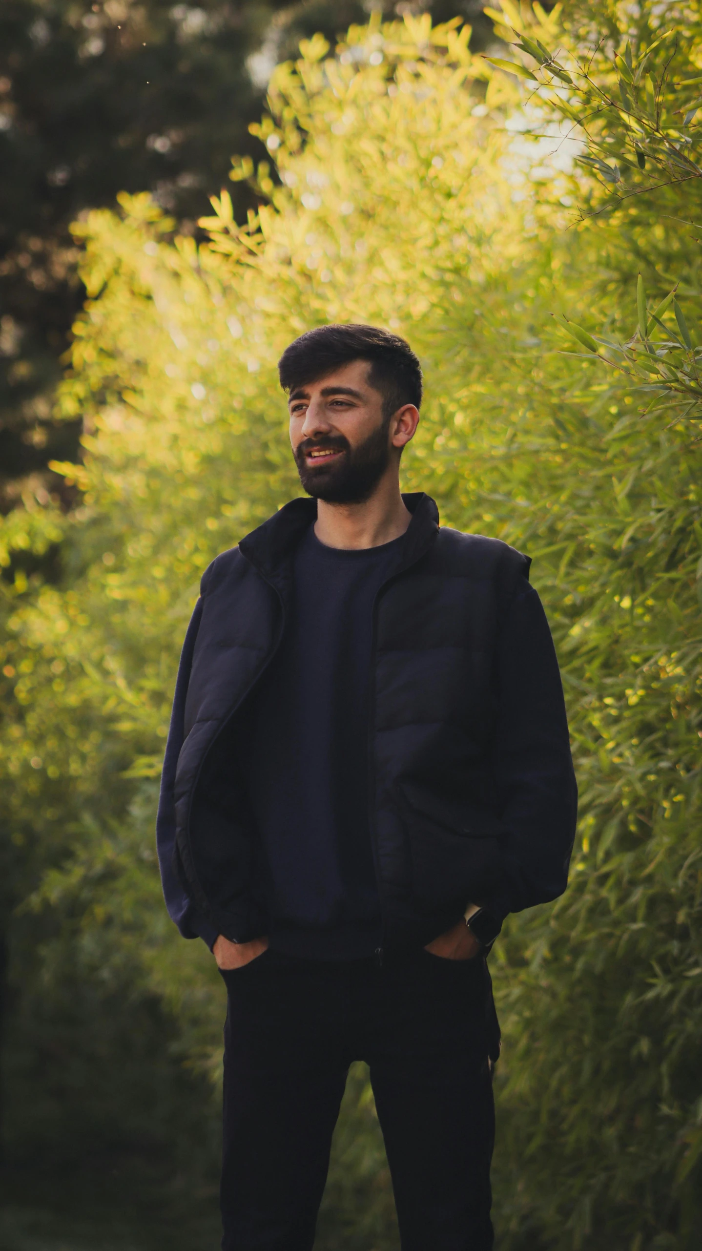 a man standing in the grass near a bush