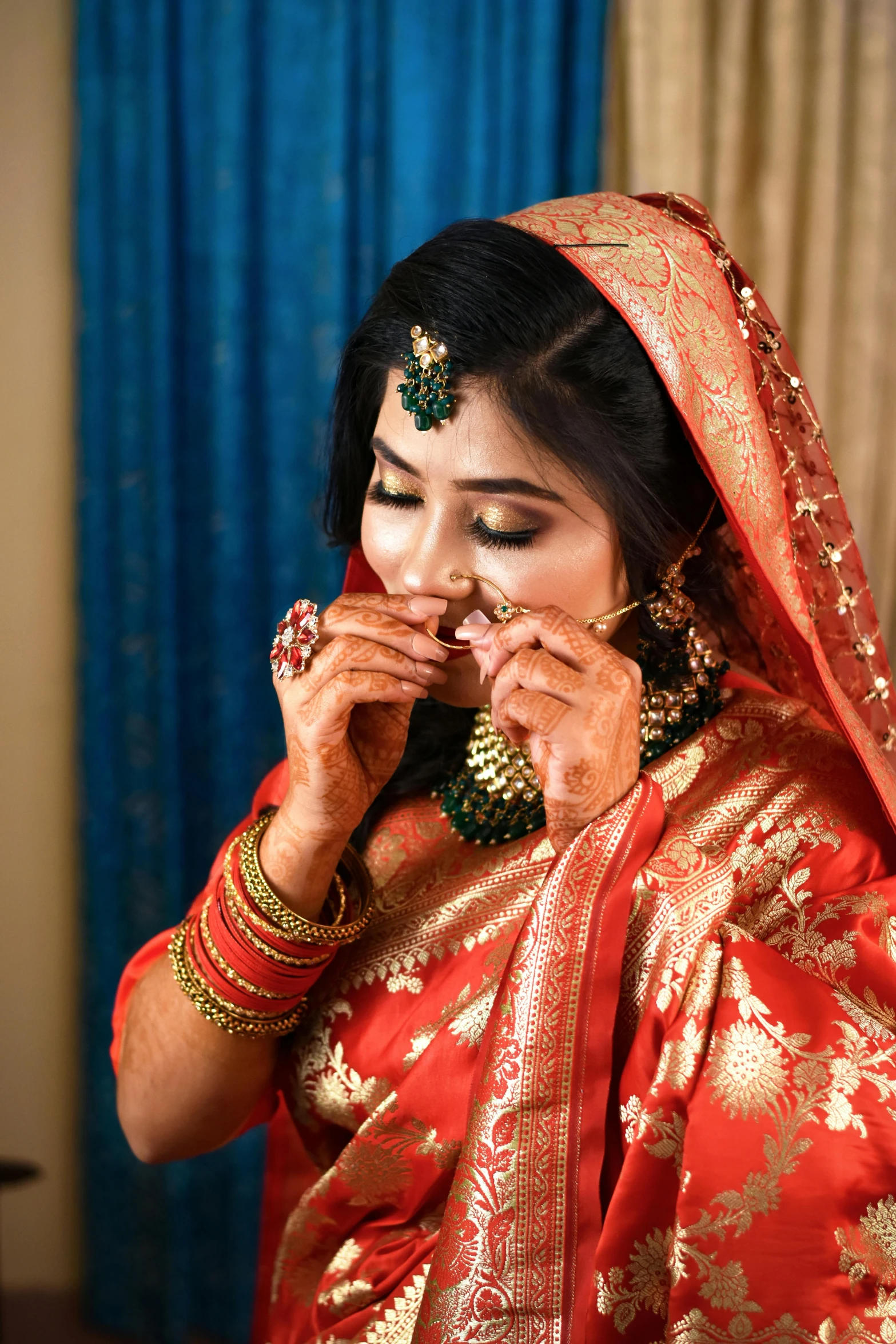 a woman in a red wedding dress putting on her jewelry