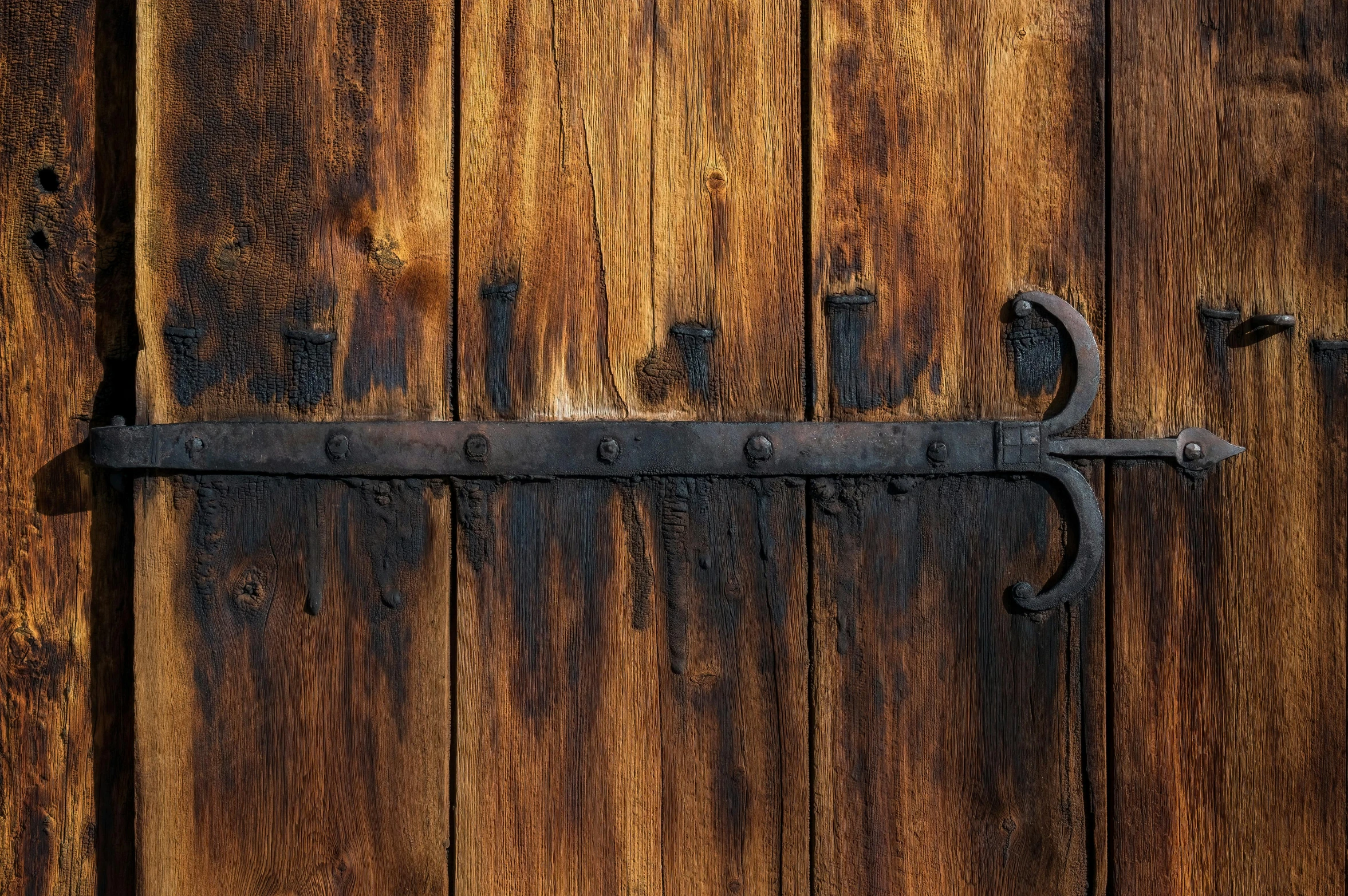 an old wood door has a rusty handle on it
