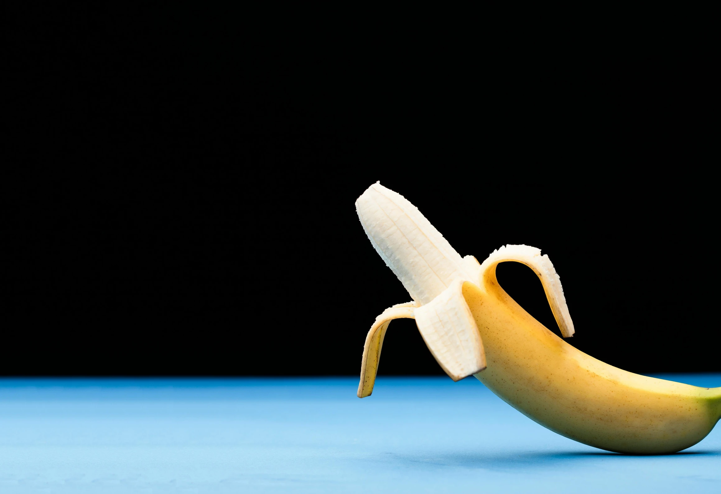 a banana peel with a bite missing on a blue surface