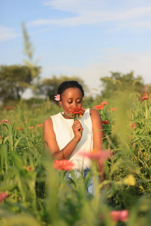 a woman smelling flowers in a large field