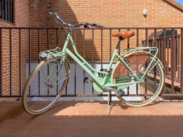 a light green bike parked in front of a fence