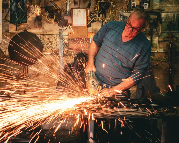 a man in glasses is using a grinder with sparks