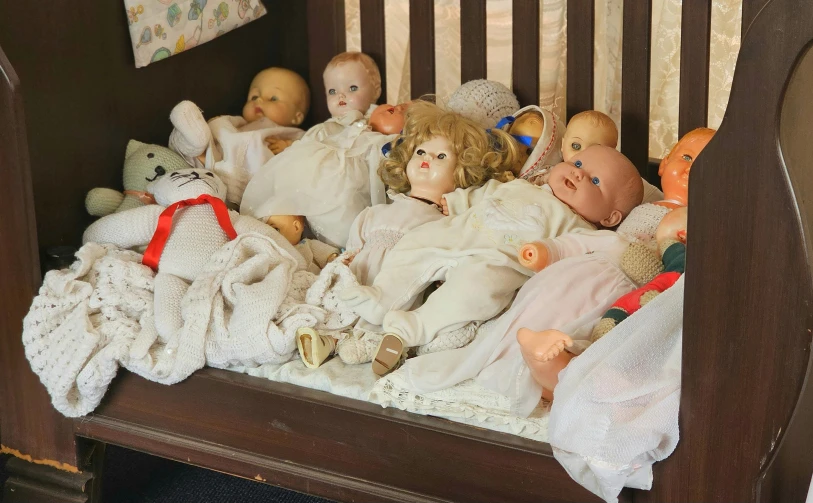 an old crib is filled with small dolls