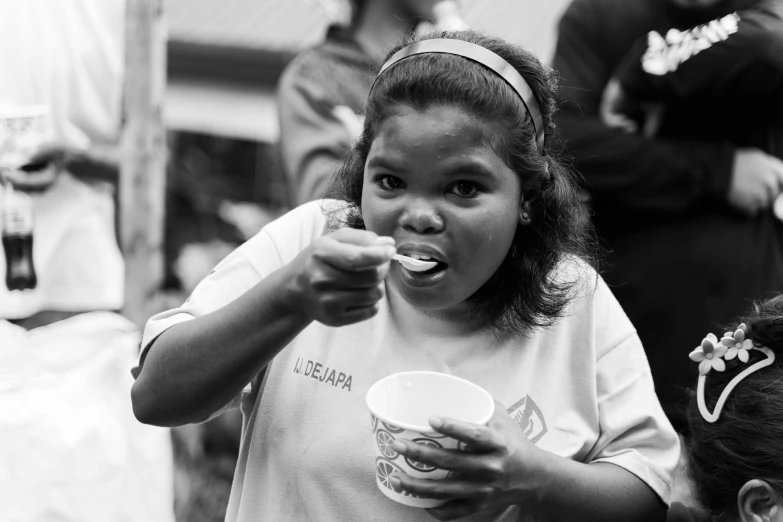 a  holding a bowl while brushing her teeth