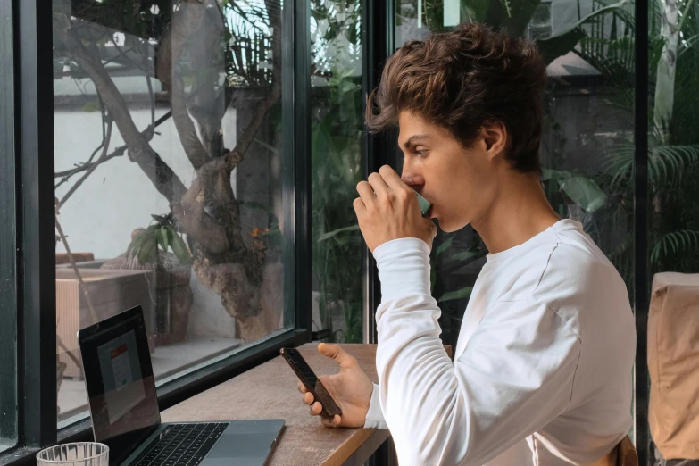 woman looking out a glassed room while typing on her laptop