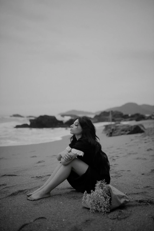 a woman sitting on the beach next to the ocean