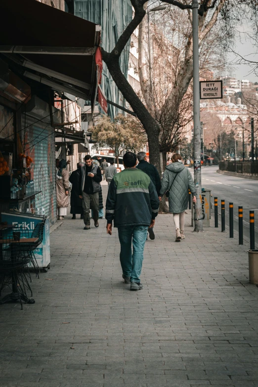 the man in the green jacket is walking down the sidewalk