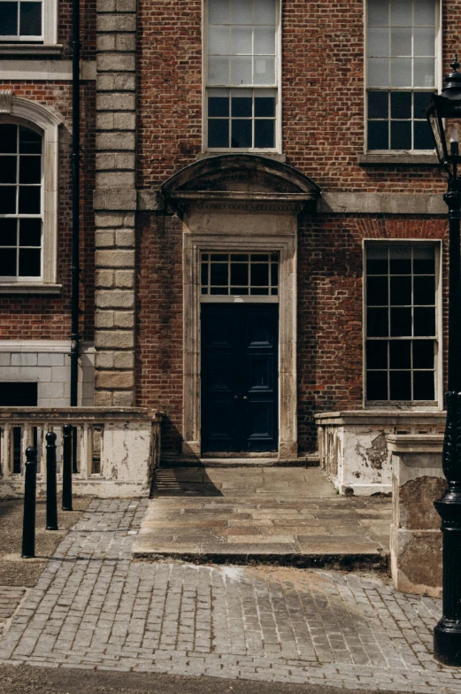 two windows are on the brick building and one has a black door