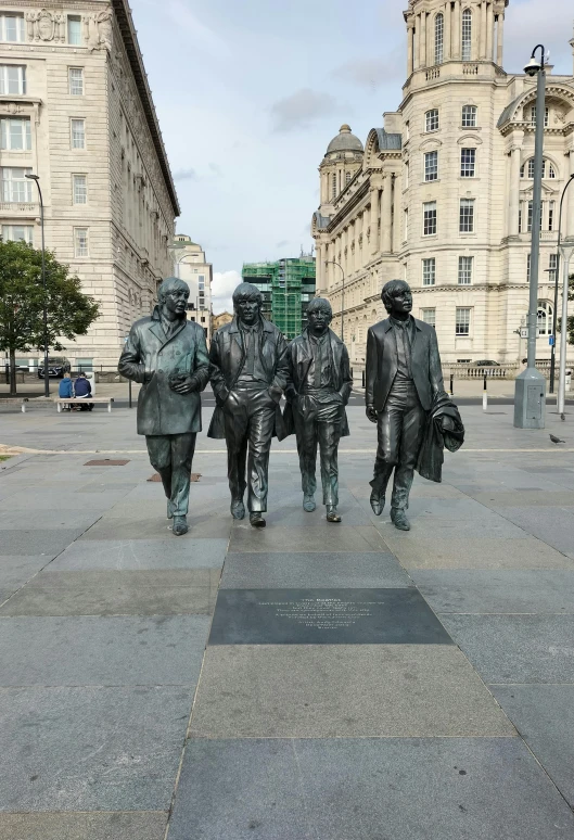 statues of people in suits walking along the street